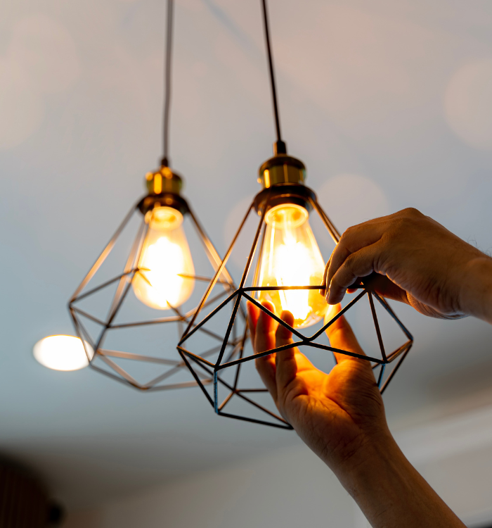 Electrician adjusting modern pendant light fixture for residential electrical service.